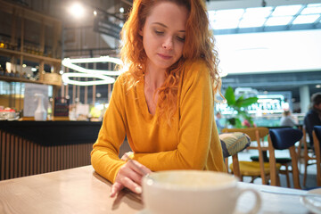 Portrait of  woman sitting in cafe at morning and using smartphone. Shopping mall