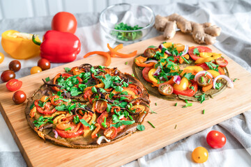 .raw vegetarian pizza with onions, peppers, tomatoes, fresh herbs on a cutting board. Lies on the...