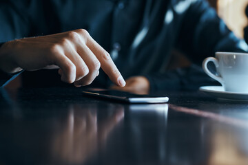 Businessman with mobile phone in cafe at table, cropped view