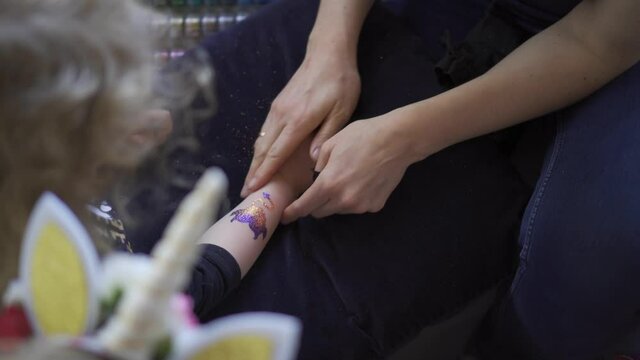 Little girl hand and temporary glue and paint tattoo make. Gimbal top view shot