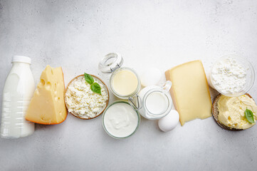 Fresh dairy products, milk, cottage cheese, eggs, yogurt, sour cream and butter on white table, top view