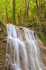 Fototapeta na wymiar Beautiful waterfall in a deciduous forest in the autumn