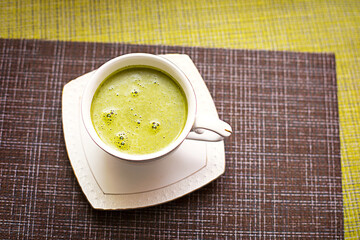 Japanese matcha green tea is poured into a white mug and on a white saucer in powder. Tea set on a textured napkin. Invigorating drink in a cafe, cooking, cheerfulness, antioxidant. space for text
