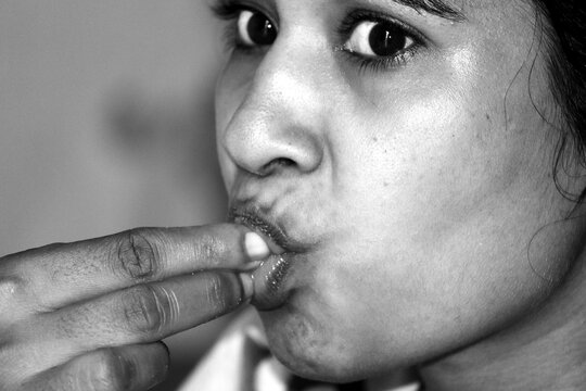 a women eating food to hand in black and white photo