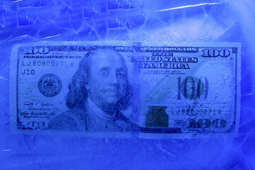 Fototapeta premium New $ 100 bill frozen under a layer of ice, the concept of the global financial crisis or the fall of the dollar on the world market