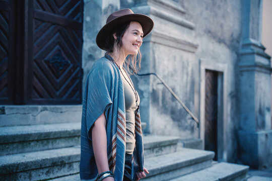 Portrait of a young beautiful woman in a hat on the background of a medieval city, travel to Europe