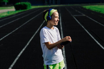 Girl jogging on a sunny summer evening, laying on treadmill, stadium, physical training, back to school.