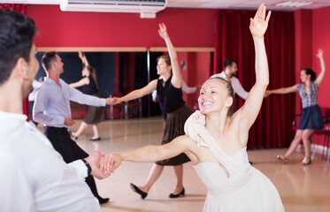 Portrait of adult dancing couples enjoying latin dances in modern studio