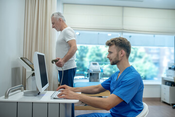 Young doctor assisting mature patient with exercise stress test