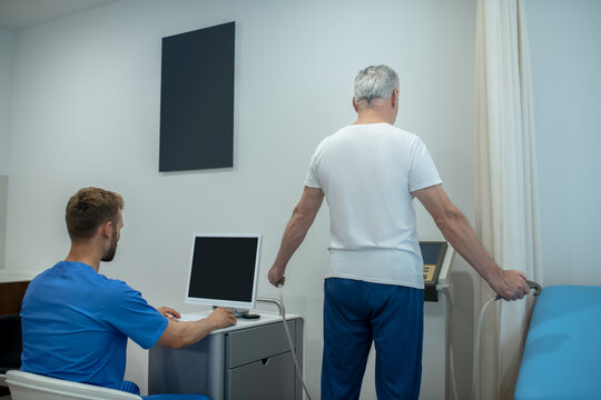 Back To Camera Gray-haired Man Standing And Sitting Doctor