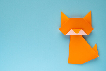 orange origami cat on sky blue background
