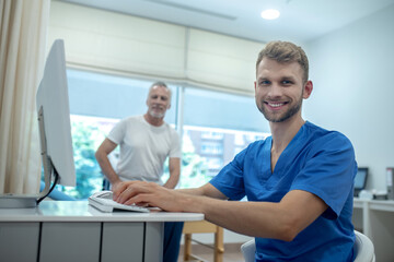Smiling young doctor and elderly patient in office