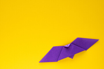 purple origami bat on yellow background