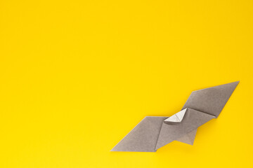 gray origami bat on yellow background