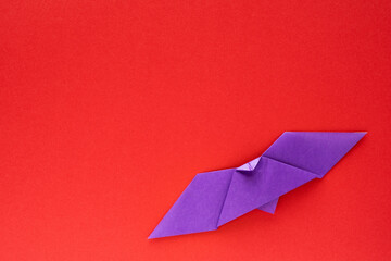 purple origami bat on red background