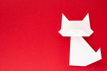 white origami cat on red background