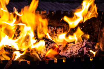 Fire on a dark background. Fire from firewood close up. Flaming burning sparks close-up, fire patterns. Red and orange Infernal glow of fire in the dark.