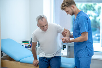 Obraz premium Elderly grayhaired man and helpful attentive doctor.