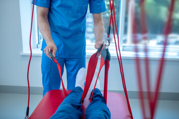 Hands of physician holding belt around patients leg