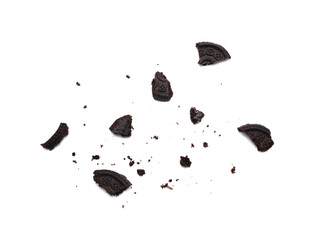 Scattered crumbs of chocolate sandwich cookies filled with sweet cream flavored isolated on white background.