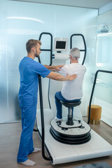 Patient sitting on simulator and supporting rehabilitation therapist