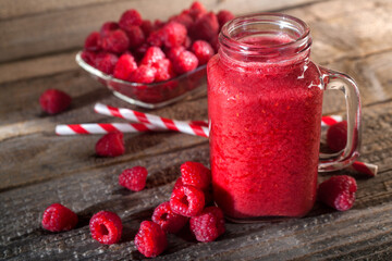 Healthy appetizer red raspberries fruit smoothie in glass jar with berries background, top view. Detox and antioxidant drink. Vintage style composition on a rustic wooden table.