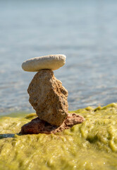 Textured stones, stacked in a pyramid, against the background of clear sea water.