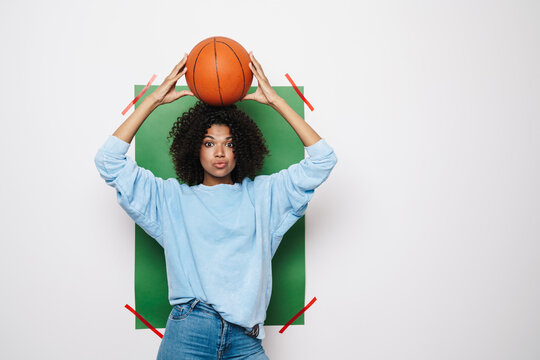 Image of african american woman posing with basketball on her head