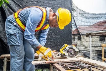 Construction worker wears protective leather gloves, with a pencil and the carpenter's square trace the cutting line on a wooden table. Construction industry, housework do it yourself.