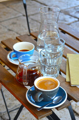 Filter coffee and espresso lungo in blue cups with pitcher of water on a wooden table outdoors