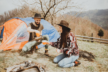 Loving couple sitting on the mountain outdoors. Man and woman travel together. Couple traveler enjoys nature, hugs, looks at the landscape near the tent