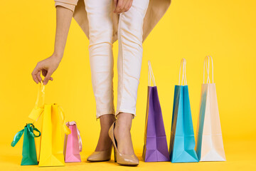 female feet in shoes packs shopping lifestyle yellow isolated background