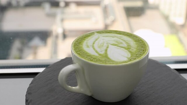 white coffee cup with green matcha latte art rotating on a stone plate side view. template for summer drink menu of cafe and restaurant

