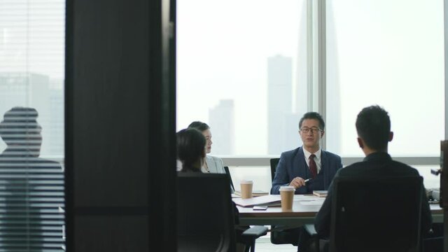 group of asian corporate executives meeting in company conference room discussing business