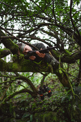 Soldier or revolutionary member or hunter in camouflage on the tree aiming the gun in his hand, hunter concept