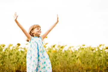 Naklejka na ściany i meble Happy girl admire nature with hands up in sunflowers field