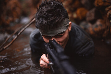 Soldier or revolutionary member or hunter aiming with gun in his hand in camouflage in the river, hunt concept