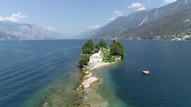Aerial view flight over Trimelone Island is an islet of Lake Garda administratively belonging to Brenzone located between Cassone and Assenza one hundred meters from the coast 4k high resolution