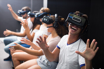 Man is watching exciting movie with friends in VR glasses in entertainment room.