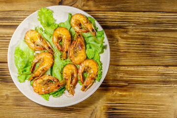 Tasty baked shrimps on a wooden table. Top view