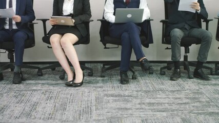 group asian corporate executives job applicants sitting in lined up chairs waiting for interview