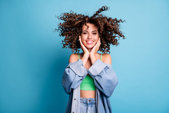 Photo of cute charming cheerful lady smiling hands cheekbones big volume extensive hairstyle home after rain wear green crop top naked abdomen denim jacket isolated blue color background