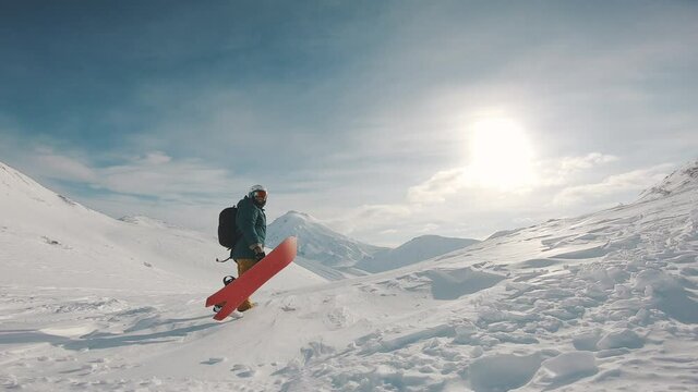 snowboarder walks uphill, holding boards, filmed on the gopro hero 8 black, frame shot on a freeride tour in Kamchatka volcanoes, filmed on the gopro 8 in protune mode