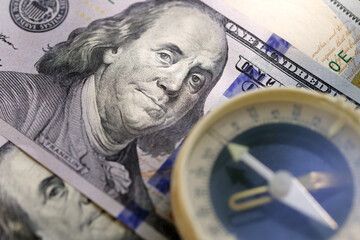 Hundred dollar bills and blurry old compass.  Close-up.  Selective focus