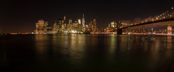Fototapeta na wymiar Panoramic night shot of New York skyline and the Brooklyn Bridge