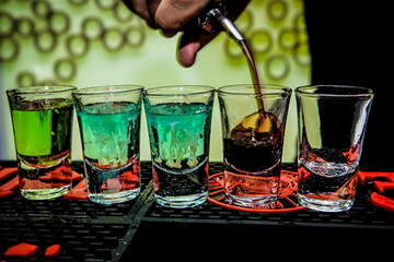 Barman preparing cold, tasty and colorful cocktails at the club 