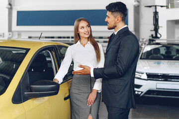 Man car dealer showing a woman buyer a new car