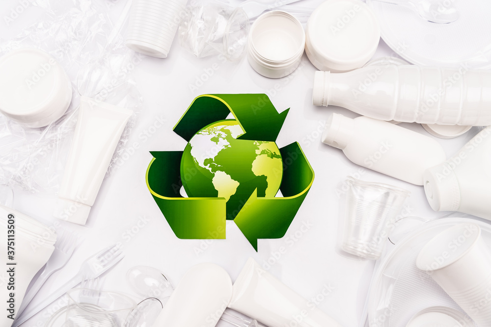 Wall mural top view of recycle sign and plastic rubbish scattered on white background