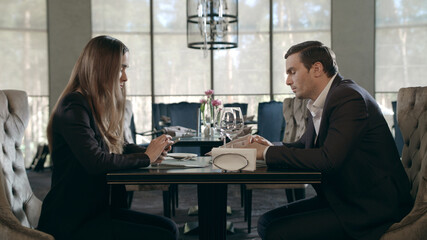 Business couple meeting in restaurant. Adult man and woman talking at cafe table
