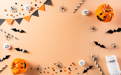 Halloween decorations made from pumpkin, paper bats and black spider on pastel orange background....
